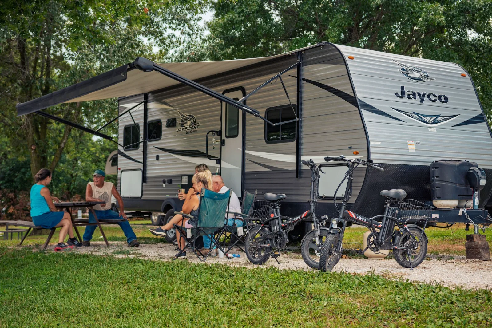 Guests relaxing at a picnic table under the awning of their travel trailer at Katy Stop RV Park